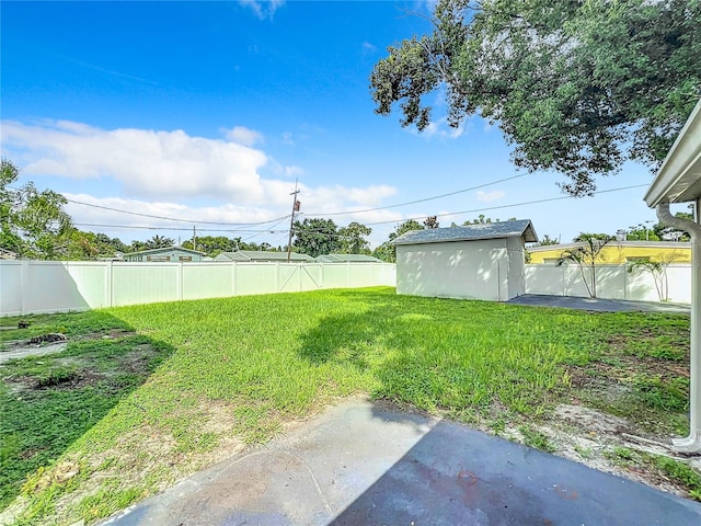 view of yard with a fenced backyard, a storage unit, and an outbuilding