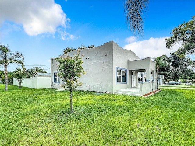 view of side of property with stucco siding, fence, and a yard