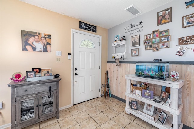 tiled foyer entrance with wooden walls and a textured ceiling