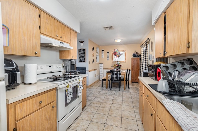 kitchen with white range, a textured ceiling, and light tile patterned floors