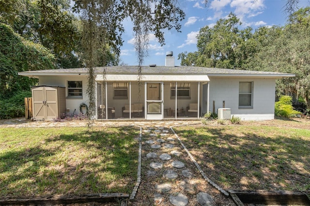 rear view of house with a yard, a storage shed, a sunroom, and central AC