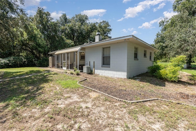 rear view of house featuring a sunroom, a lawn, and central AC