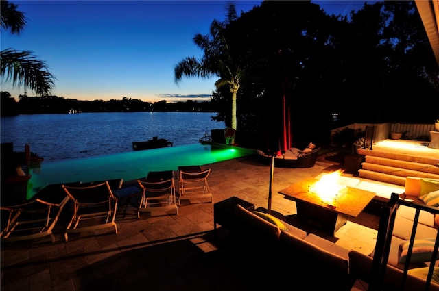 patio terrace at dusk with a water view and a fire pit