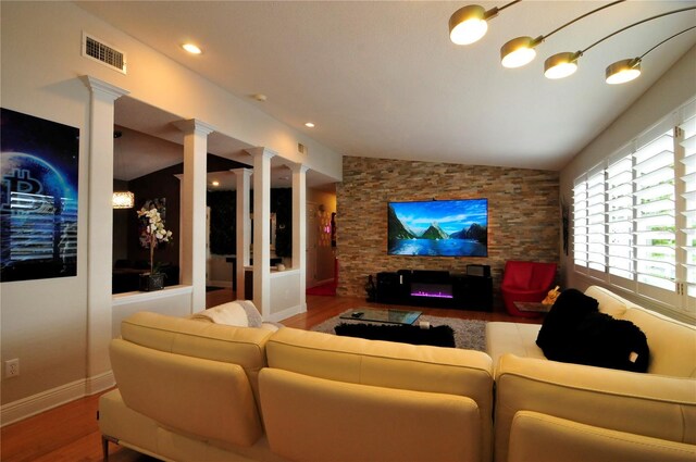 living room featuring decorative columns, lofted ceiling, and hardwood / wood-style flooring