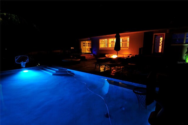 pool at night with a patio area