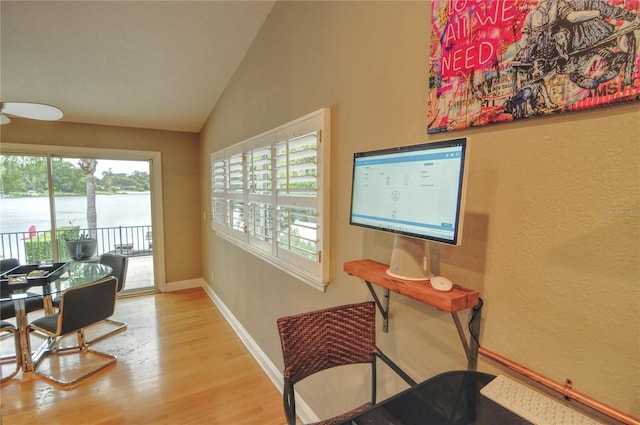 interior space with wood-type flooring, a water view, and vaulted ceiling