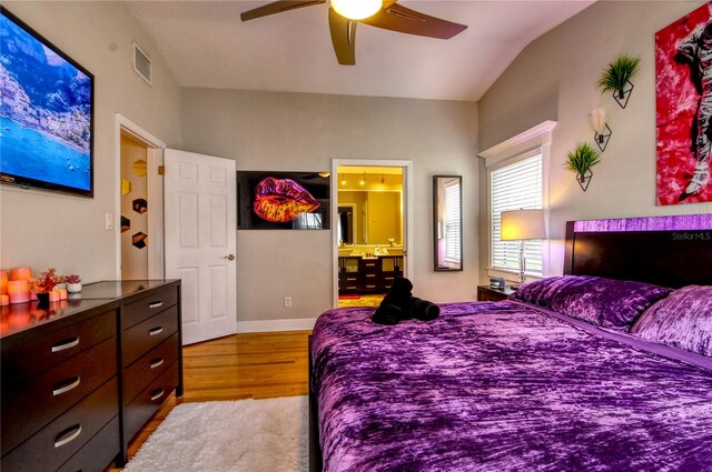 bedroom featuring ensuite bath, vaulted ceiling, light hardwood / wood-style floors, and ceiling fan