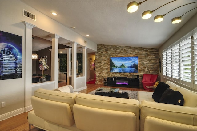 living room with wood-type flooring, lofted ceiling, a textured ceiling, and ornate columns