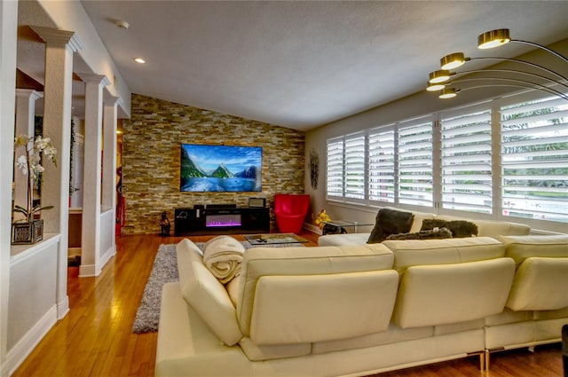 living room with hardwood / wood-style flooring, lofted ceiling, ornate columns, and a healthy amount of sunlight