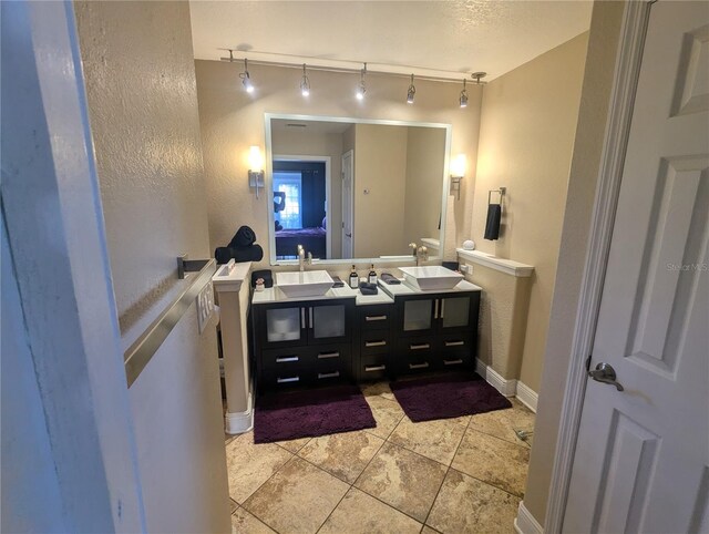 bathroom with tile patterned flooring, vanity, and rail lighting