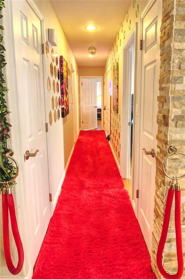 hallway with baseboards and dark colored carpet