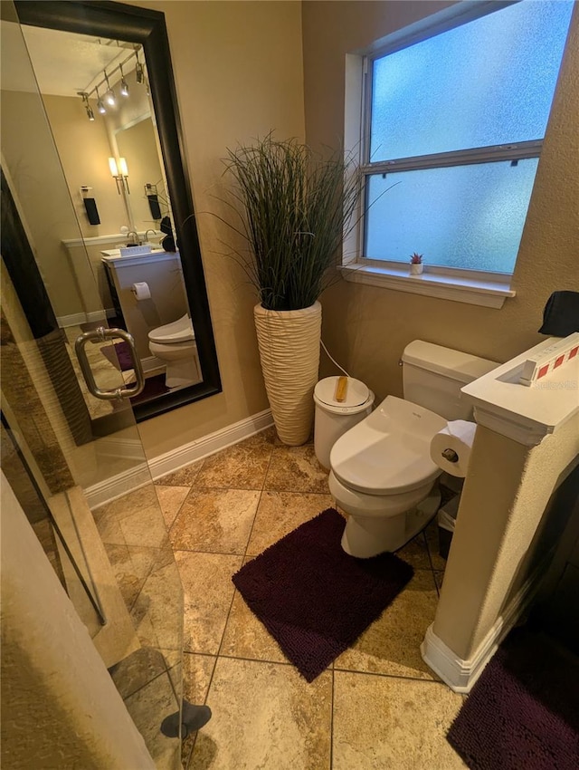 bathroom featuring track lighting, toilet, vanity, and baseboards