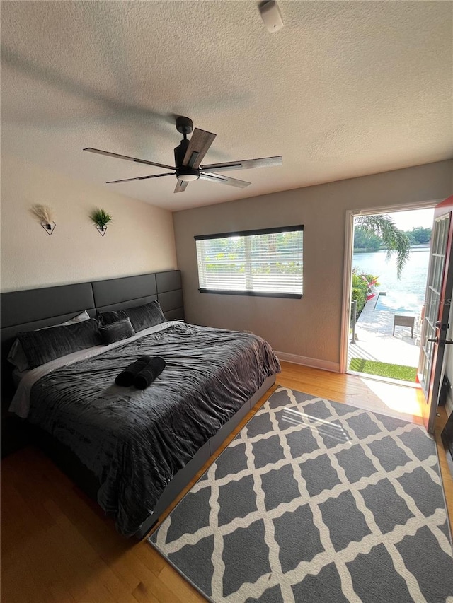 bedroom featuring ceiling fan, multiple windows, and wood finished floors