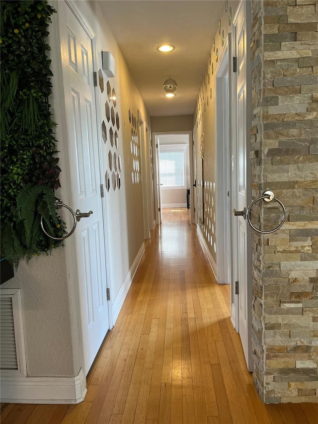 corridor with baseboards and light wood finished floors