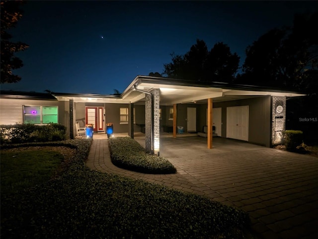 view of front of home featuring driveway, an attached carport, and covered porch