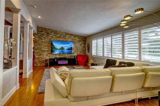 living room featuring baseboards, decorative columns, wood finished floors, and lofted ceiling