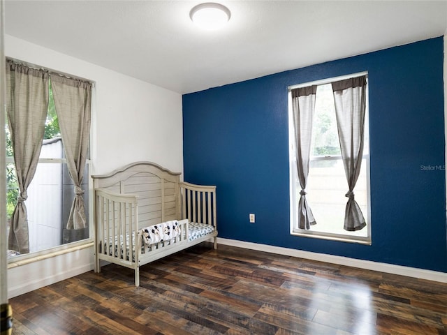 bedroom with a crib and dark hardwood / wood-style floors