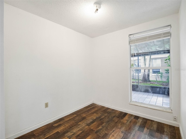 empty room with a textured ceiling and dark hardwood / wood-style flooring