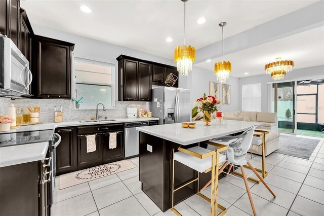 kitchen featuring hanging light fixtures, sink, appliances with stainless steel finishes, a center island, and an inviting chandelier