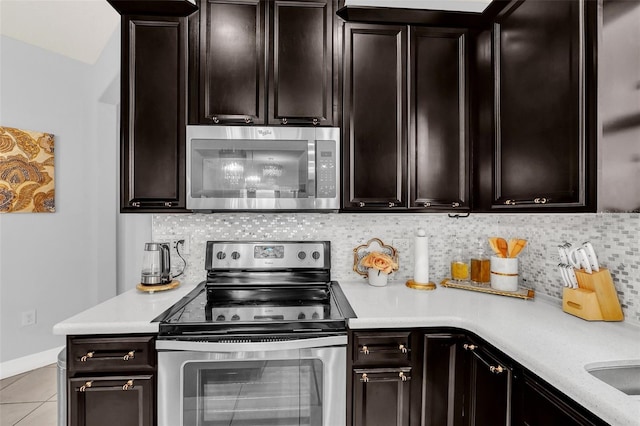 2599 Nouveau Way, Kissimmee, FL 34741 - kitchen featuring light tile patterned floors, baseboards, stainless steel appliances, light countertops, and backsplash