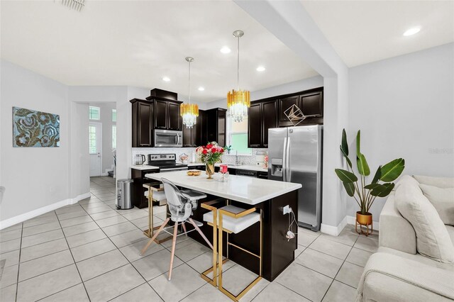 kitchen with appliances with stainless steel finishes, decorative backsplash, a breakfast bar, a kitchen island, and pendant lighting