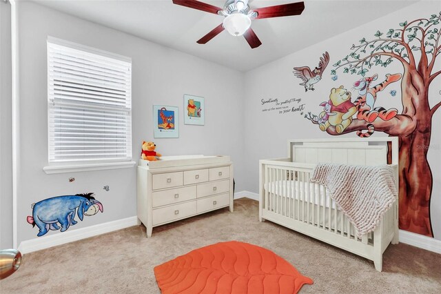 bedroom featuring a crib, ceiling fan, and light colored carpet