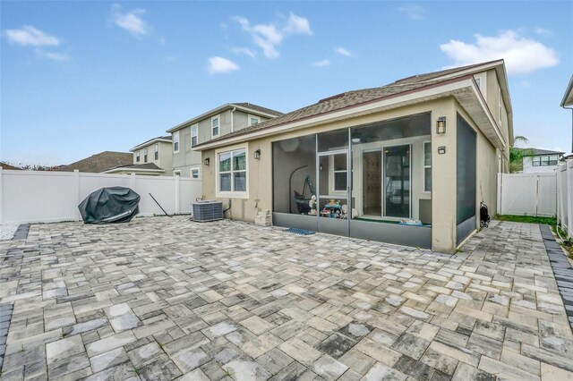 back of property with cooling unit, a sunroom, and a patio area