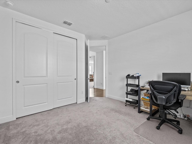 carpeted office with a textured ceiling