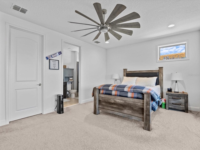 carpeted bedroom with ceiling fan, a textured ceiling, and ensuite bath