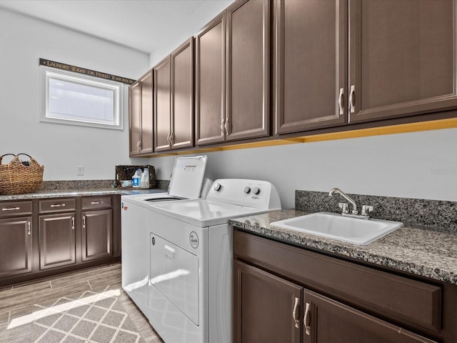 laundry room with sink, independent washer and dryer, cabinets, and light hardwood / wood-style floors