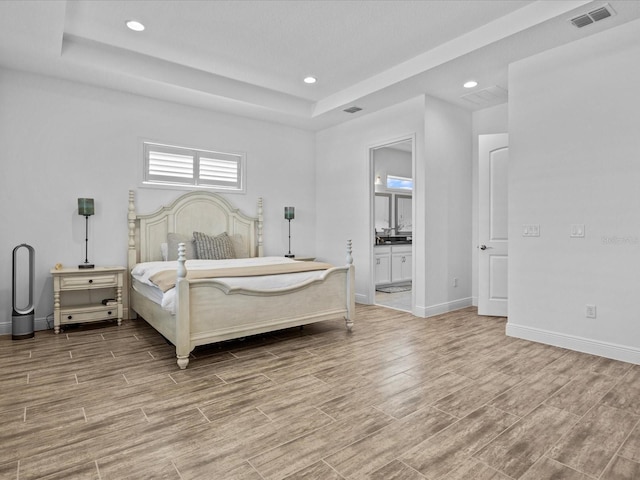 bedroom with ensuite bathroom and a raised ceiling