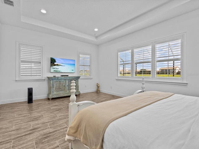 bedroom featuring a tray ceiling and light wood-type flooring