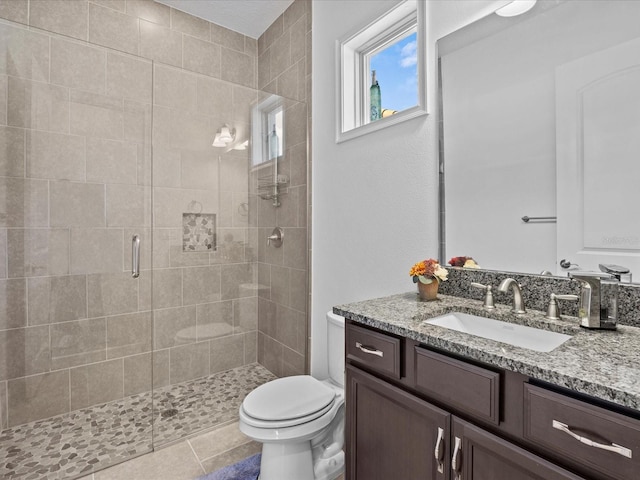 bathroom featuring toilet, a shower with shower door, vanity, and tile patterned floors