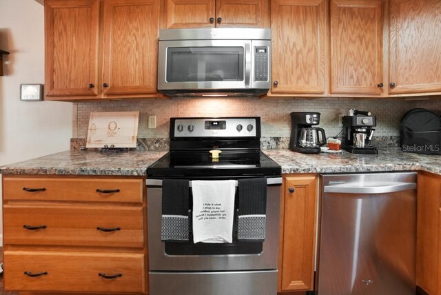 kitchen with appliances with stainless steel finishes, light stone counters, and tasteful backsplash