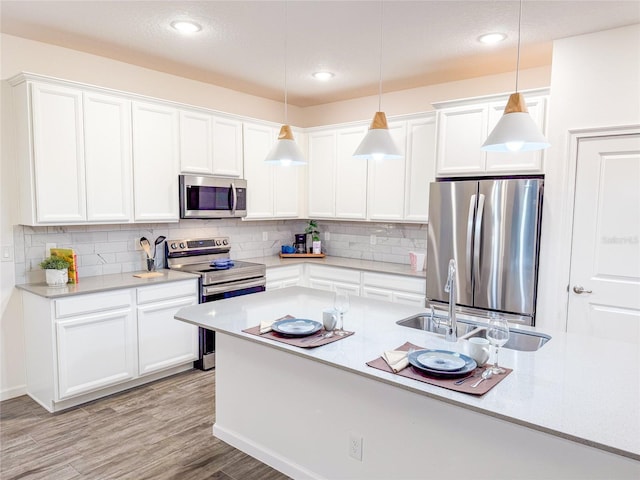 kitchen featuring stainless steel appliances, light hardwood / wood-style flooring, decorative light fixtures, decorative backsplash, and white cabinets