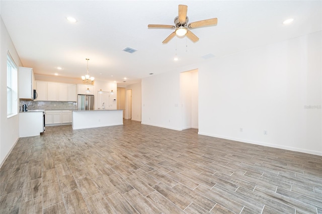 unfurnished living room featuring sink and ceiling fan with notable chandelier