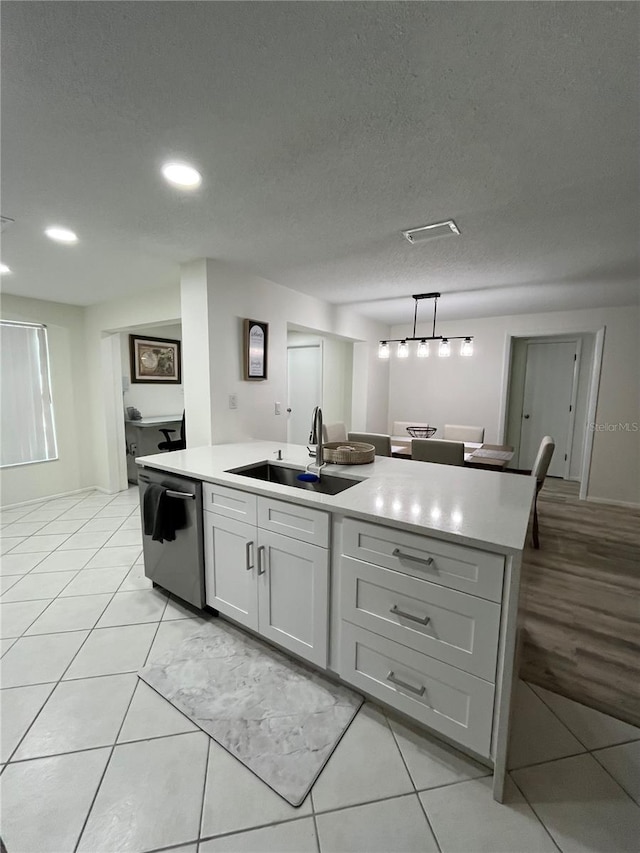 kitchen featuring an island with sink, dishwasher, a textured ceiling, and sink