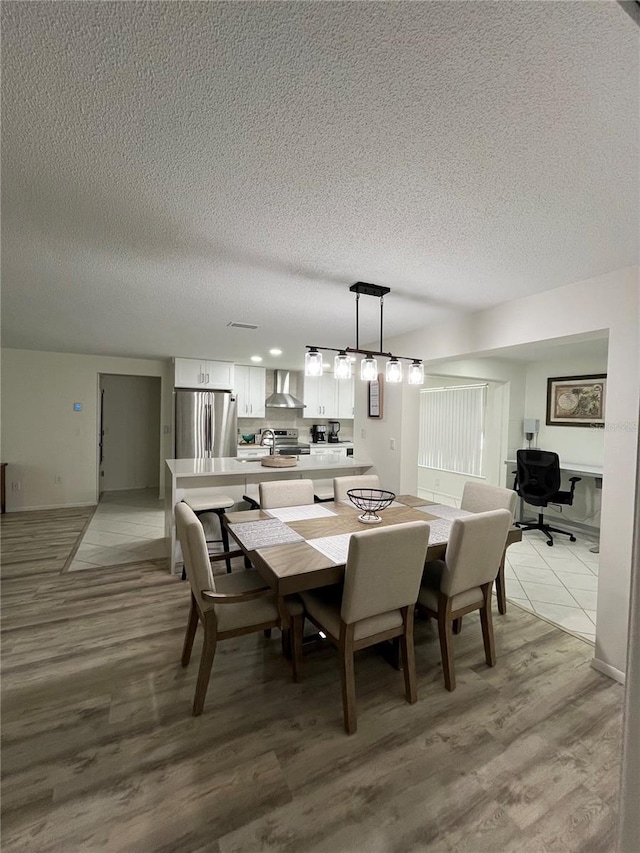 dining area with light hardwood / wood-style floors and a textured ceiling