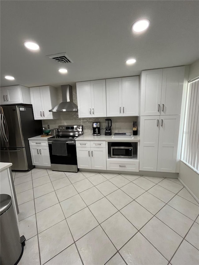 kitchen with appliances with stainless steel finishes, decorative backsplash, wall chimney exhaust hood, and white cabinets