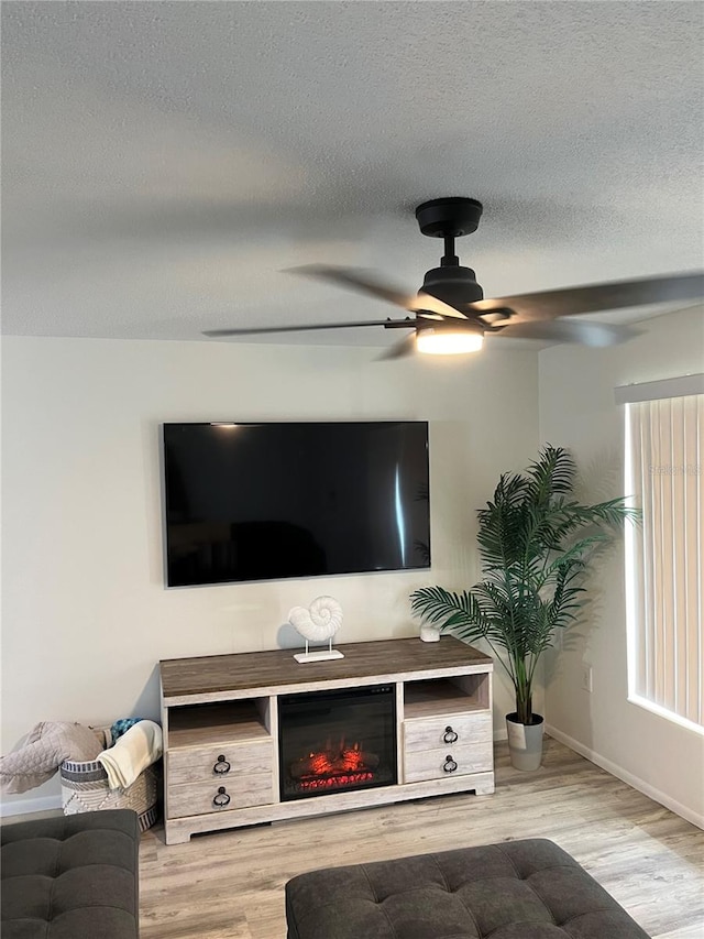 living room with a textured ceiling, ceiling fan, and hardwood / wood-style flooring