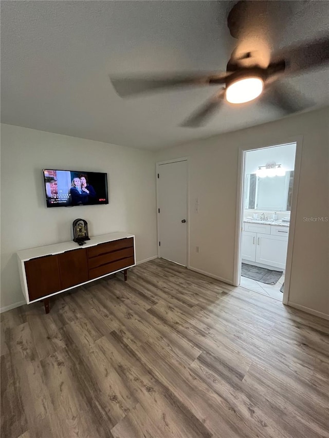 unfurnished living room featuring ceiling fan, a textured ceiling, light wood-type flooring, and sink