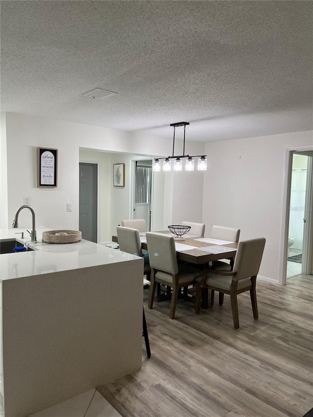 dining space featuring a textured ceiling, sink, and light hardwood / wood-style flooring