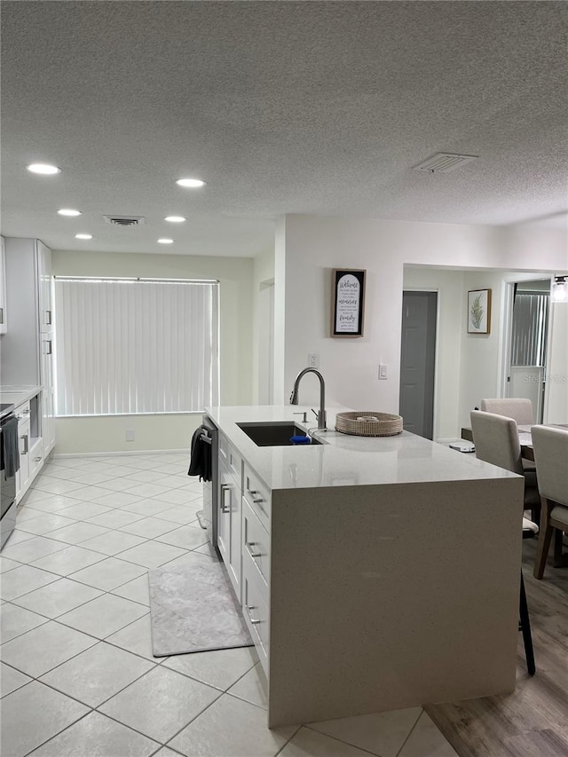 kitchen with a textured ceiling, white cabinetry, and sink