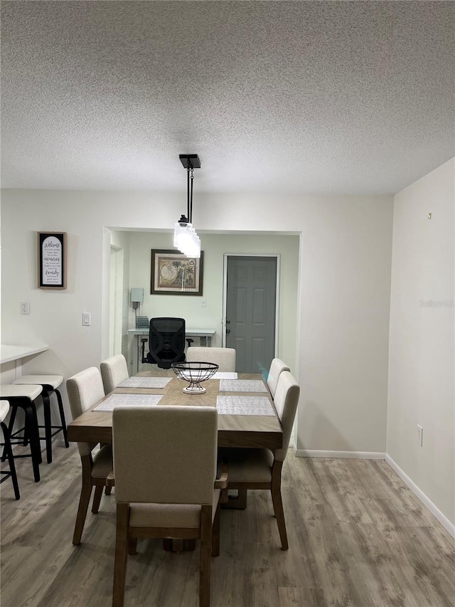 dining space featuring wood-type flooring and a textured ceiling