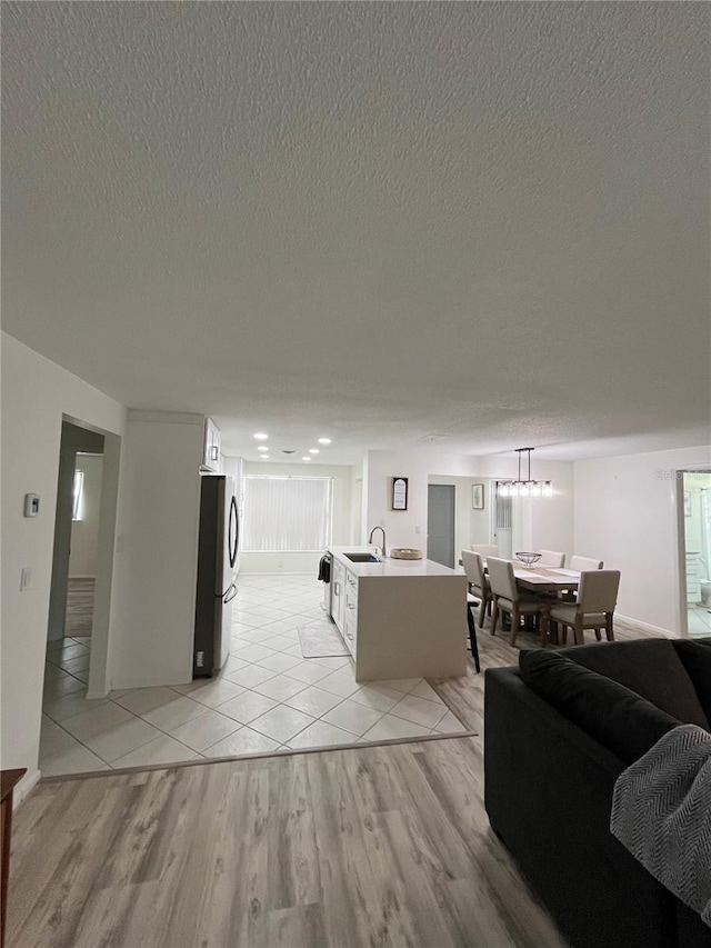 living room featuring a textured ceiling, sink, and light hardwood / wood-style flooring