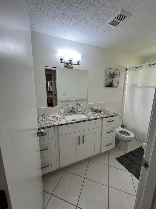 bathroom with tile patterned flooring, a textured ceiling, vanity, and toilet