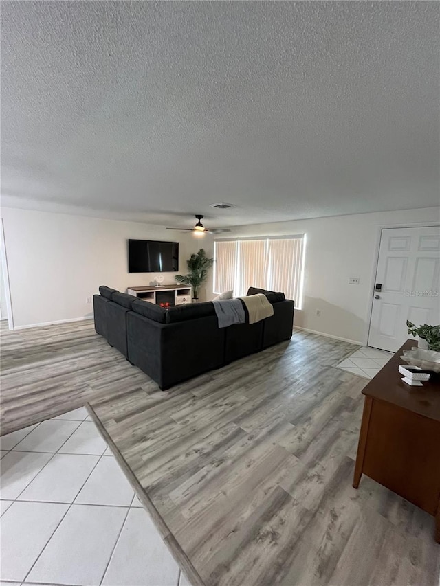 living room featuring light wood-type flooring, a textured ceiling, and ceiling fan