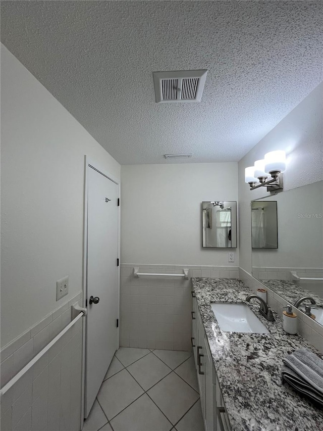 bathroom featuring tile walls, a textured ceiling, an inviting chandelier, tile patterned floors, and vanity