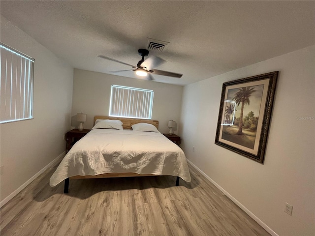 bedroom with light hardwood / wood-style flooring, ceiling fan, and a textured ceiling