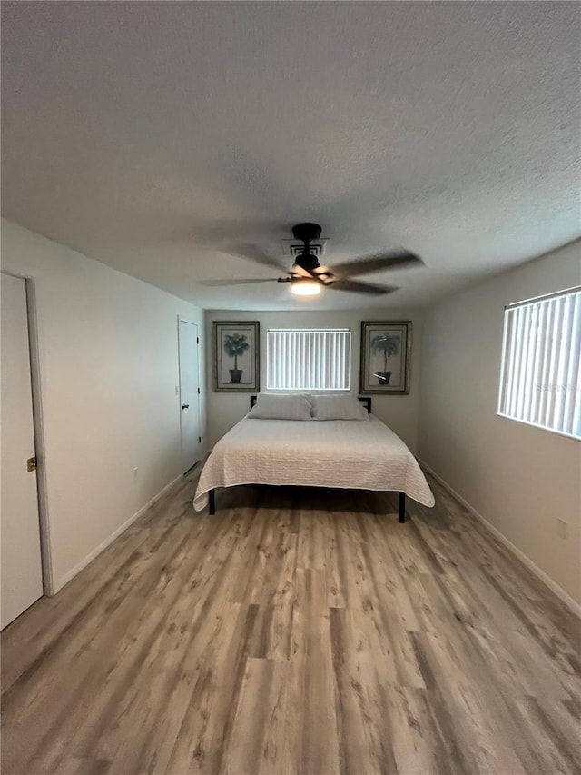 unfurnished bedroom with multiple windows, hardwood / wood-style floors, and ceiling fan